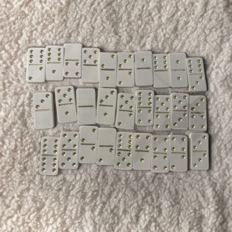 Ensemble de dominos fait main en crème avec des détails dorés, emballé dans un sac en lin.